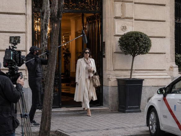 Rodaje de una actriz saliendo de un portal de un edificio elegante en Madrid